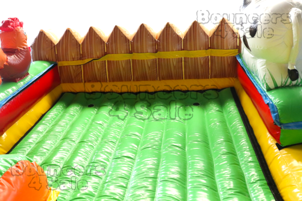 A green inflatable slide with a fence around it.