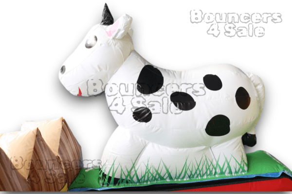 A cow inflatable sitting on the grass.