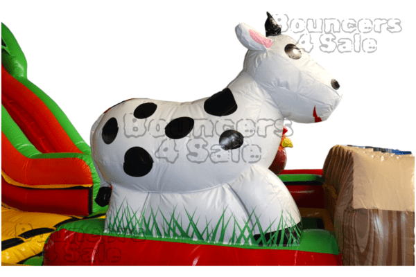 A cow inflatable sitting on top of grass.