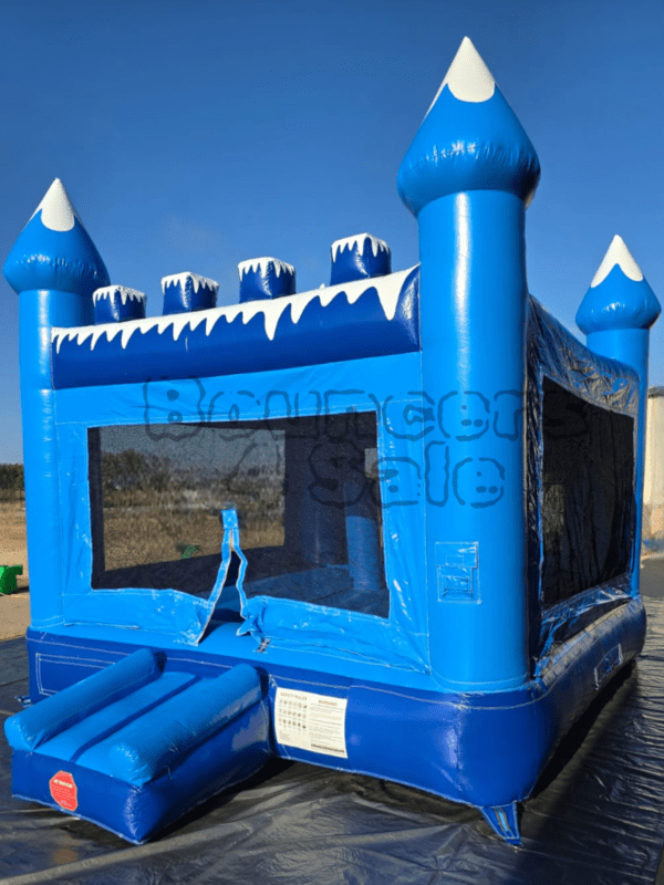 A blue inflatable castle with snow on it.