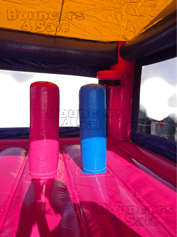 A pink and blue inflatable castle with two red barrels.