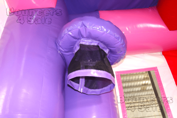 A purple and pink inflatable castle with a black tunnel.